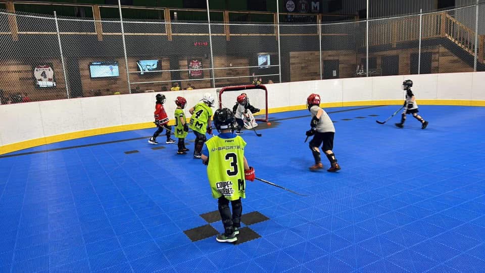 Jeunes joueurs de dek hockey sur la surface intérieure du DHG
