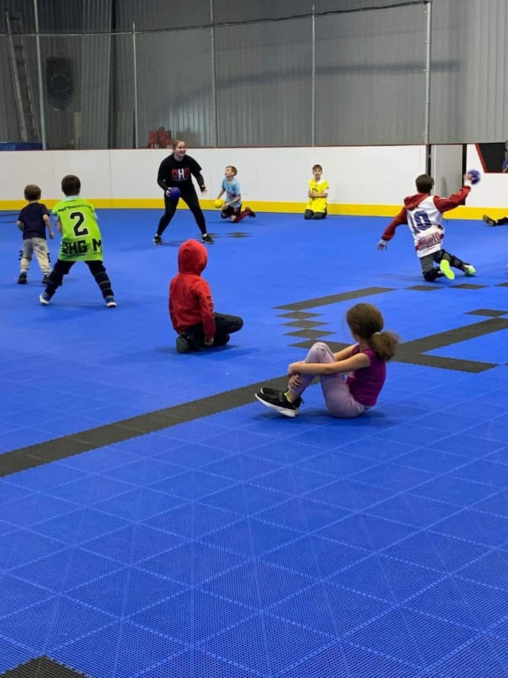 Des campeurs participent à un jeu de ballon avec une animatrice au DHG