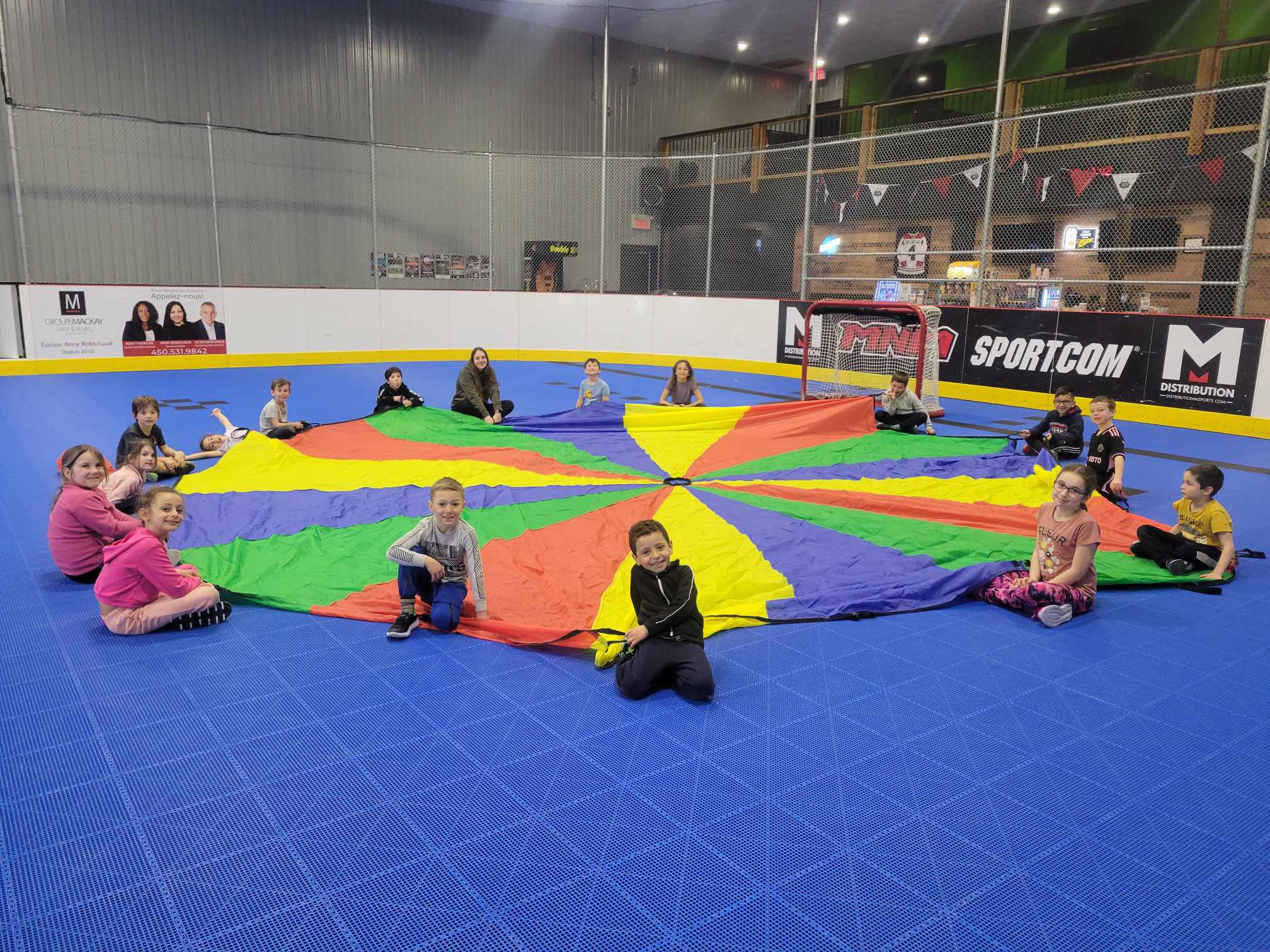 Des enfants et leurs moniteurs jouent avec un parachute multicolore