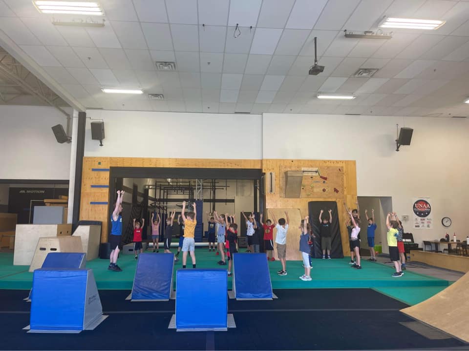 Des enfants participent à une activité dans un gymnase avec des modules sportifs